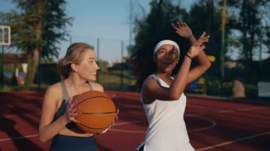Mutlu aşırı neşeli genç kız arkadaşlar basketbol sahasında birlikte vakit geçiriyorlar. Kameraya poz veren genç kadınlar sarılıp gülüyor. Arkadaşlık, spor ve aktif yaşam tarzı konsepti