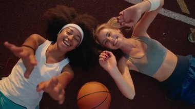 Mutlu, çekici, güler yüzlü genç spor kızları basketbol sahasında kameraya bakarak gülümsüyorlar.