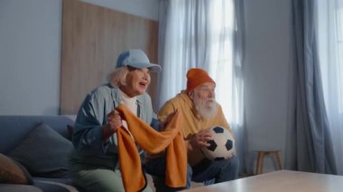 Evde televizyonda futbol maçı izleyen çok mutlu yaşlı bir çift. Mutlu, olgun bir aile heyecanlı, şallar sallıyor ve futbol topunu elinde tutuyor.