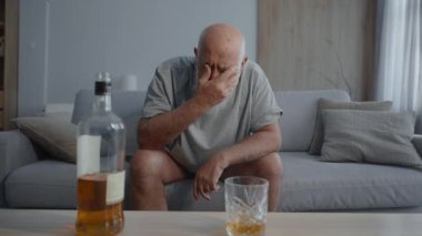 Oturma odasındaki kanepede tek başına içki içen üzgün son sınıf öğrencisi. İçki zararlı bir alışkanlık ve alkol bağımlılığı