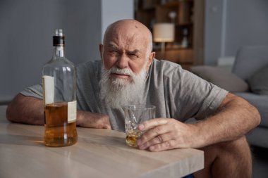 Yaşlı adam evde tek başına içki içiyor. İçki zararlı bir alışkanlık ve alkol bağımlılığı