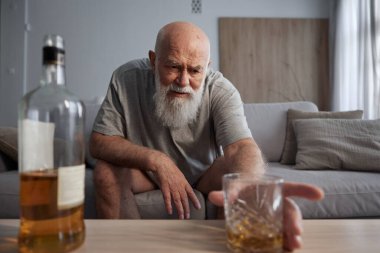 Yaşlı adam evde tek başına içki içiyor. İçki zararlı bir alışkanlık ve alkol bağımlılığı
