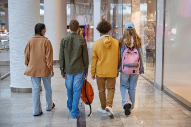 Alışveriş merkezinin koridorunda koşuşturan bir grup genç. Mutluluk, dostluk ve gençlik yaşam tarzları