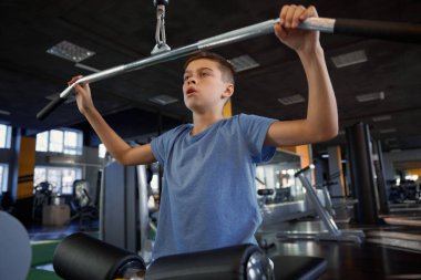 Modern spor malzemelerinde vücut ve kas geliştirme eğitiminin keyfini çıkaran ilham verici genç çocuk.