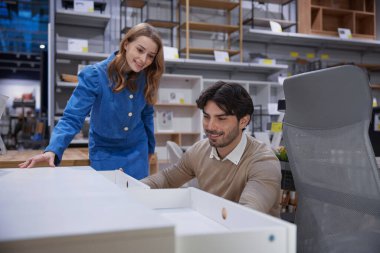 Sevgili çift, çağdaş bir perakende satış alanında çeşitli şık ofis mobilyası seçeneklerini aktif olarak keşfediyor.