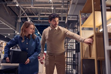 Modern bir mobilya mağazasında modern tasarımlar sergileyen bir çift mutlu bir şekilde gezer ve alışveriş yapar.