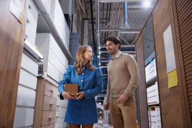 Mobilya mağazasında sırada yürüyen genç bir çift.