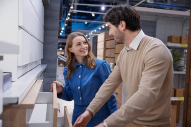 Mobilya mağazasında sırayla yürüyen sevimli genç bir çift.