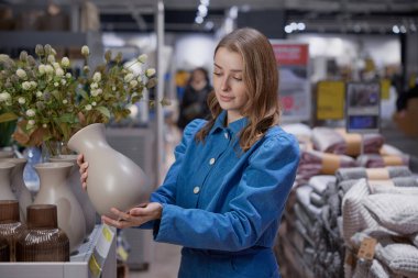 Genç bir kadın bugün şık bir ev eşyası dükkanından güzel bir vazo seçiyor.