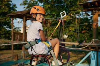 Oyuncu küçük kız halat parkındaki engelleri aşarken Hawser 'ı çekiyor. Dayanıklılık gelişimi ve çocuklar için aktif aşırı boş zaman aktivitesi