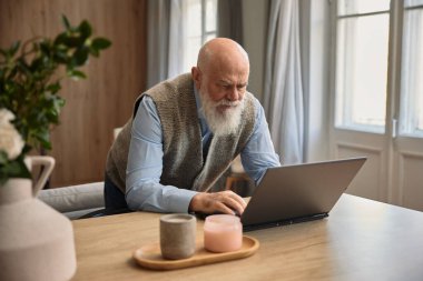 Üst düzey adam internette dizüstü bilgisayar kullanıyor ya da evdeki sosyal medyada iletişim kuruyor. Yaşlılar ve modern teknoloji kavramı