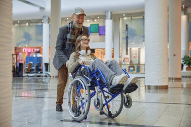 Neşeli, yaşlı bir adam tekerlekli sandalyedeki genç bir kızı nazikçe itiyor ve hayatımızdaki neşeli anları vurguluyor.