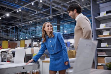 Sevgili çift, çağdaş bir perakende satış alanında çeşitli şık ofis mobilyası seçeneklerini aktif olarak keşfediyor.