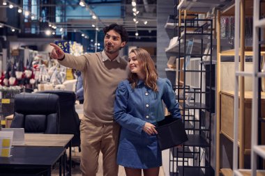 Modern bir mobilya mağazasında modern tasarımlar sergileyen bir çift mutlu bir şekilde gezer ve alışveriş yapar.