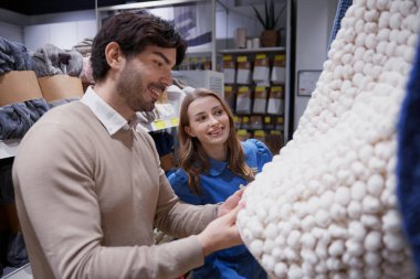 Modern bir mağaza ortamında tekstil araştırması yapan bir çift.