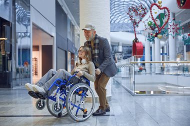 Neşeli, yaşlı bir adam tekerlekli sandalyedeki genç bir kızı nazikçe itiyor ve hayatımızdaki neşeli anları vurguluyor.