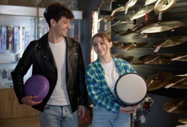 Bir mağazada, bir erkek ve bir kadın neşeyle bir tef ve canlı bir mor balo tutuyorlar, birlikte eğlenceli aktiviteler yapıyorlar.