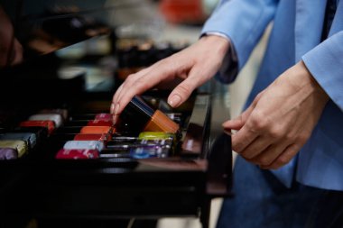 Eller şık bir rafta sergilenen canlı tırnak cilasından dikkatlice seçiyor.