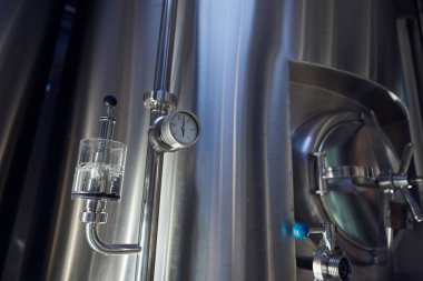 Yapısının üstüne monte edilmiş manometreyle donatılmış endüstriyel paslanmaz çelik tank, süreçlerdeki zamanlamayı gösteriyor