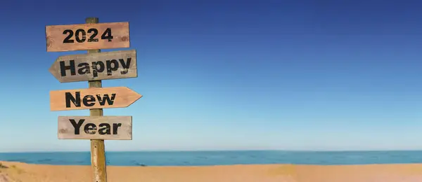 2024 青空のビーチの前に方向標識に書かれた幸せな新年 ストックフォト