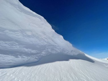 Mavi gökyüzü ile kayak yamacının kenarındaki bir yamacı kaplayan taze kar yakın plan. 
