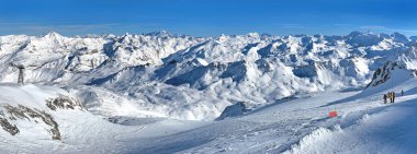Tignes 'teki Fransız Alplerinde karlı dağ sıraları ve kayak yamacı mavi gökyüzünün altında tatil yapıyor.