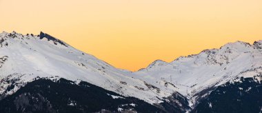Alp Vadisi 'ndeki karlı dağ zirvesinde gün batımı 