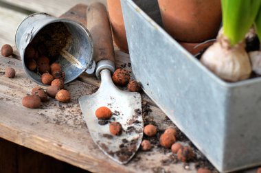 Yakın plan kil topları ve kürekte toprak metal bir kutunun içine yerleştirilmek üzere ahşap bir masaya konur. 