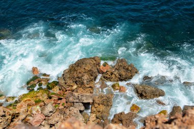 Algarve 'deki Portekiz sahillerinde köpük oluşturan kayalara çarpan dalgalarla denizin tepesinden manzara 