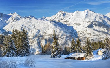 Dağda kış manzarası, mavi gökyüzünün altında karla kaplı ve Tarentaise 'de bir kayak merkezinde dağ evi. Fransa.