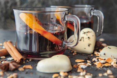  portakal dilimlenmiş şarap bardaklarda kalp şeklinde kurabiyeler ve baharatlar gri bir arkaplanda dizilmiş. 