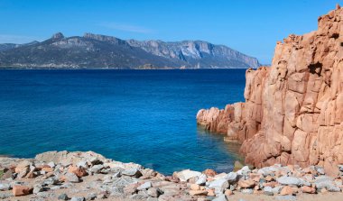 Sardinya 'da berrak bir denizin kenarındaki kırmızı granit kaya - Rocce Rosse Arbatax