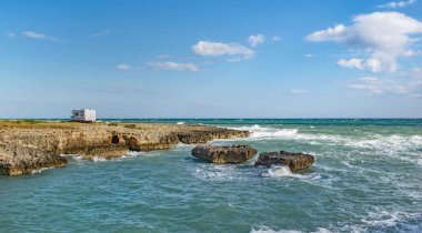 Deniz kenarına park etmiş bir karavan. Kayalık bir sahilde. 