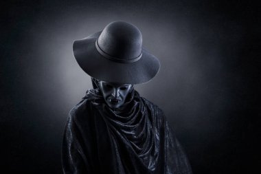 Vampire with old hat over dark misty background