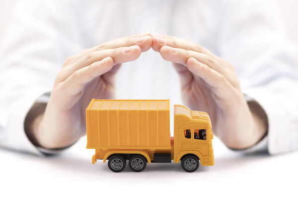 Yellow cargo delivery truck miniature protected by hands