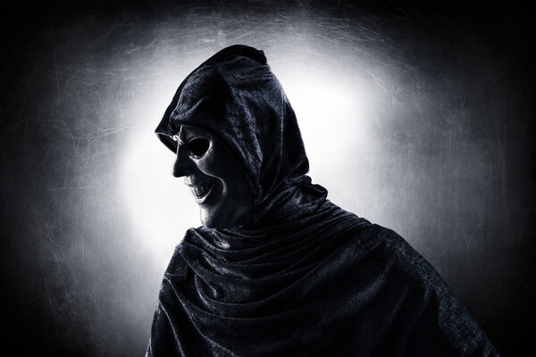 Scary figure with hooded cloak in the dark