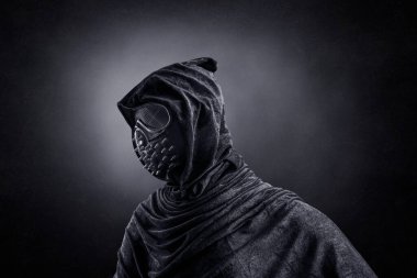 Kapüşonlu, çivili pelerinli, gece karanlığında sisli arka plan maskeli korkunç bir şahıs.