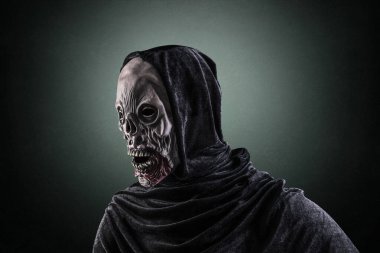 Koyu yeşil sisli arka planda kapüşonlu bir zombi portresi.