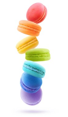 Canlı gökkuşağı renklerinin ortasında uçan badem kurabiyeleri, beyaz arka planda izole edilmiş.