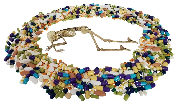 Prone Skeleton和显示吸毒危险的药丸 免版税图库照片
