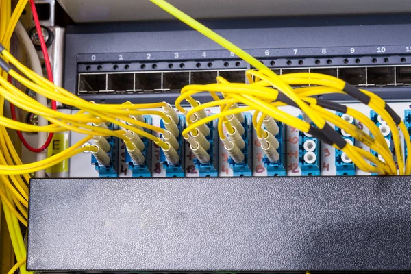 fiber optic cables plugged in network switch panel inside data center