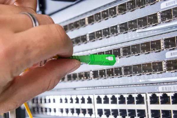 Tangan Dari Administrator Yang Menancapkan Kabel Serat Optik Kedalam Switchboard Stok Gambar