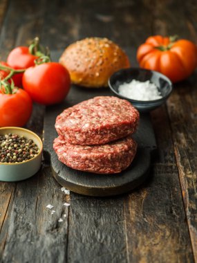 Ahşap bir masanın üzerinde çiğ hamburger köfteleri