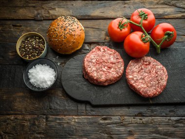 Ahşap bir masanın üzerinde çiğ hamburger köfteleri