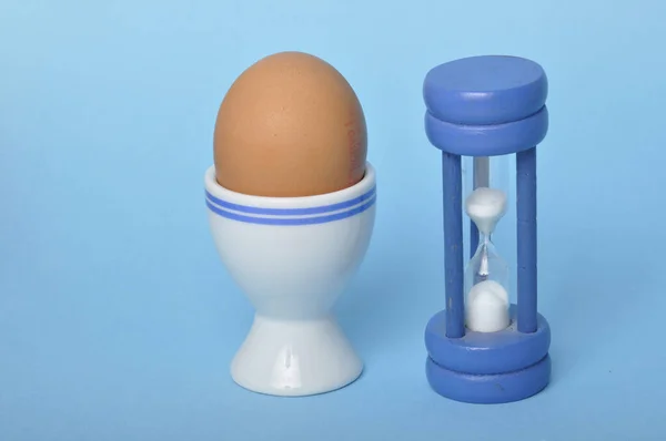 Βραστό Αυγό Και Κλεψύδρα Μπλε Φόντο Εικόνα Αρχείου