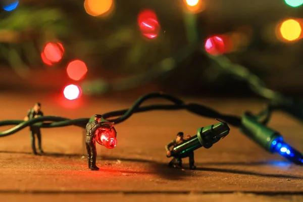 Miniature Workers Managing Christmas Lights Royalty Free Stock Photos