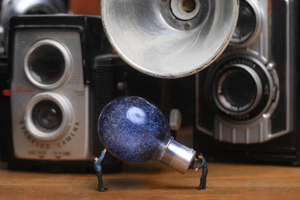 Miniaturarbeiter Hantieren Mit Oldtimer Glühbirne Und Kamera lizenzfreie Stockfotos