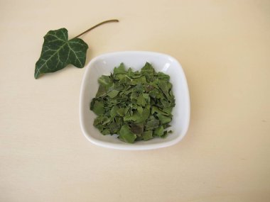 Küçük bir porselen kasede kurutulmuş ve kesilmiş sarmaşık yaprakları, Folia Hederae helicis