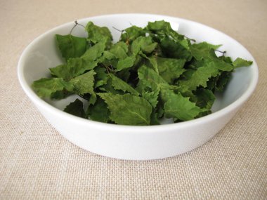 Porselen bir kasede kurumuş huş yaprağı ve bitki çayı.