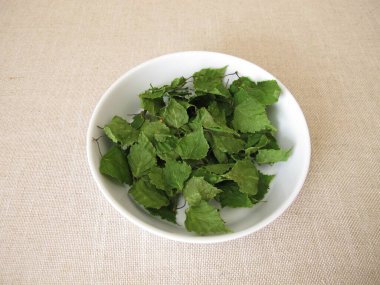 Porselen bir kasede kurumuş huş yaprağı ve bitki çayı.